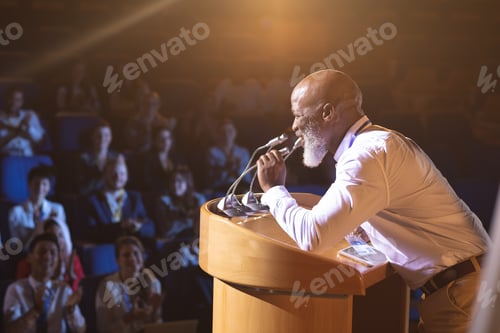 Preview: Old businessman standing and holding speaker to speak in the auditorium