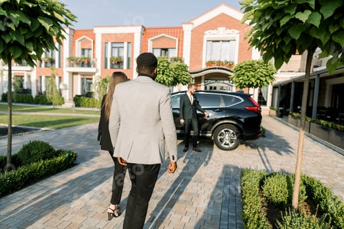 Preview: Back view of business couple, African man and Caucasian woman partners, walking to the black car on