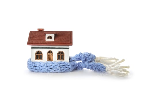 Preview: House model with knitted scarf on white background. Heating concept