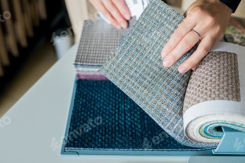 Preview: woman choosing fabrics swatches for sofa in store. Interior designer looking materials for home