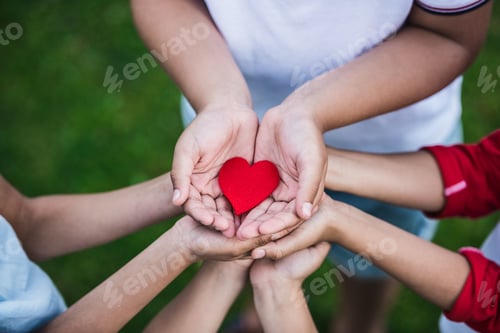 Preview: Close-up partial view of children holding red heart symbol outdoors