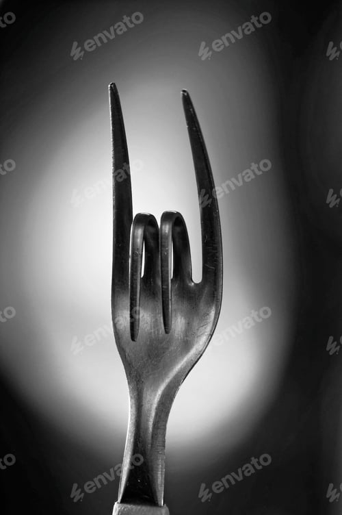Preview: Vertical greyscale shot of a bent metal fork symbolizing the sign of rock music