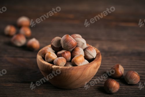 Preview: Pile of hazelnuts filbert in a wooden bowl on a dark wooden background