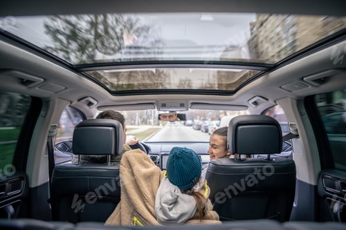 Preview: Rear view. Little girl sitting in back seat of car during family trip.