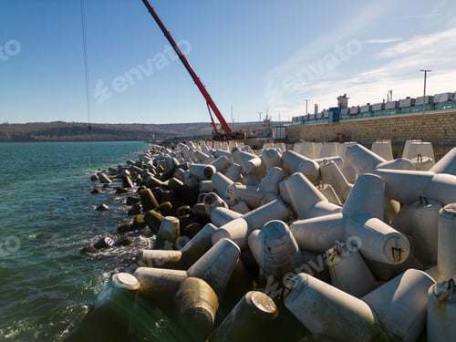 Preview: Aerial view of breakwater construction. Bulldozer and crane on a pile of boulders in the sea