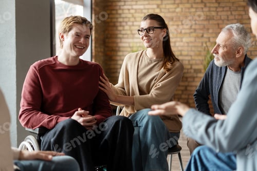 Preview: Psychotherapist comforting young man in wheelchair during group therapy session