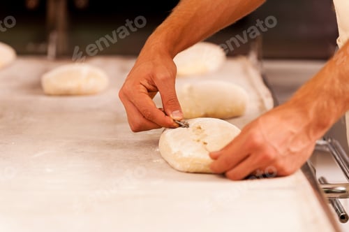 Preview: Cutting the dough. Close-up of male hands cutting the dough with special knife