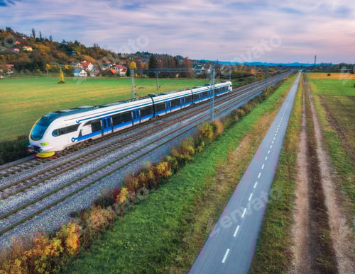 Preview: Aerial view of modern high speed train moving near alpine mountains and green fields, bike path