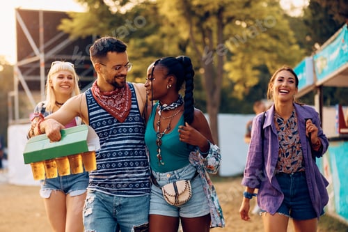 Preview: Cheerful friends carrying package of draft beer while attending summer music festival.