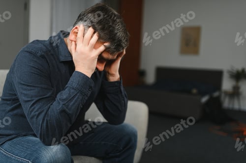 Preview: Middle age grey-haired man stressed sitting on sofa at home