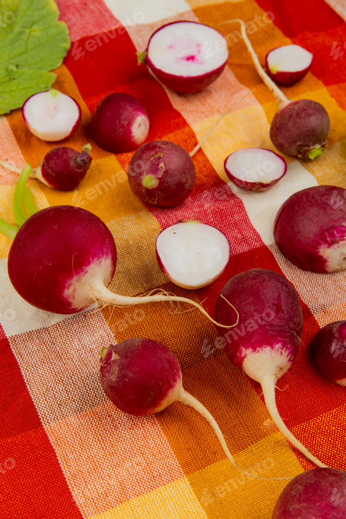 Preview: side view of pattern of cut and whole radishes on plaid cloth background decorated with leaves