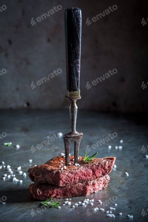 Preview: Medium rare steak with rosemary on metal table