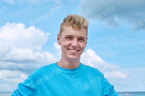 Preview: Headshot portrait of handsome smiling teenage guy, blue sky