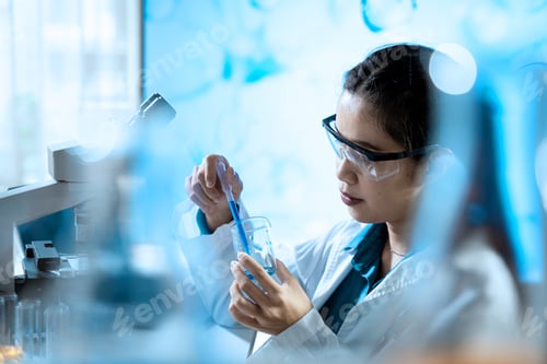 Preview: A woman in a lab coat is holding a test tube and a pipette