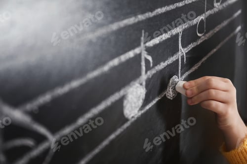 Preview: Child writing music notes on blackboard, closeup