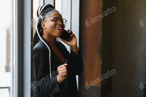 Preview: smiling black woman talking on the phone while resting in a cafeteria, selective focus