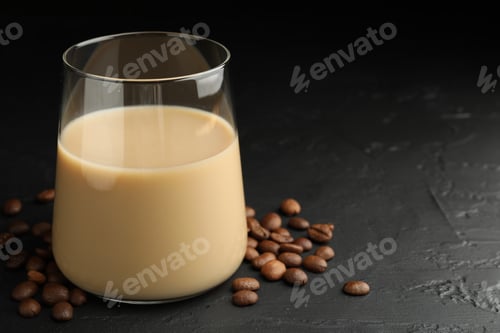 Preview: Coffee cream liqueur in glass and beans on black table, closeup. Space for text