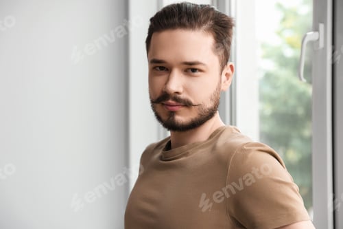 Preview: Handsome man standing near window indoors. Space for text