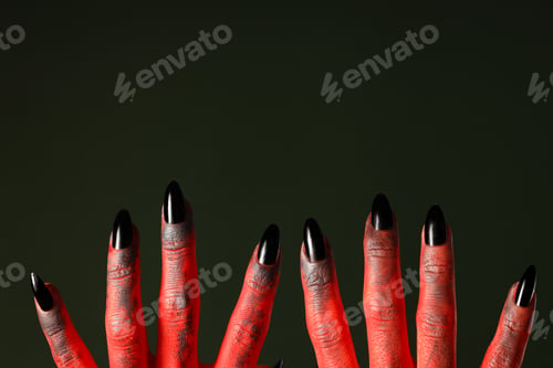 Preview: Red female hands with black nails on green background, space for text