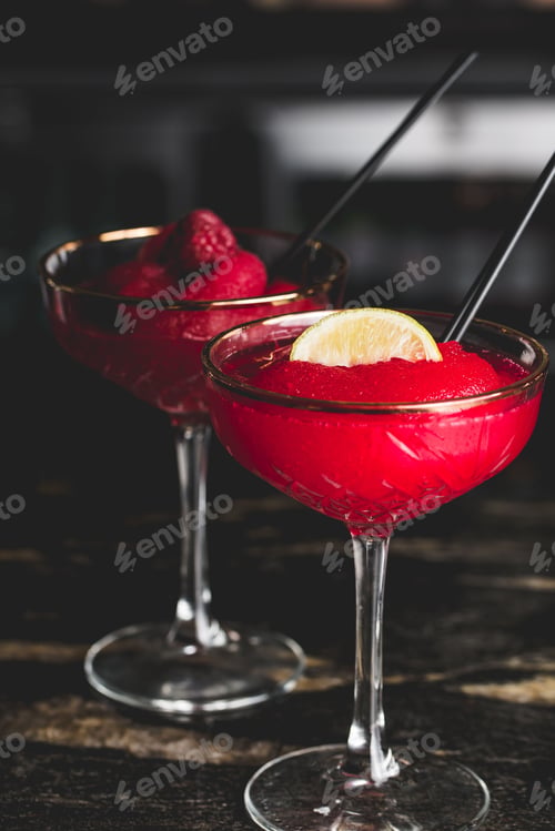 Preview: Vertical shot of a glass of Cosmopolitan cocktail and raspberry martini on bar counter