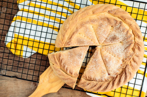 Preview: separating a piece from a round cake with a yellow napkin, On a wooden background, Top view