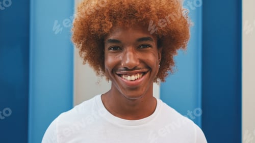 Preview: Close up, guy looks with smile at the camera on striped wall background