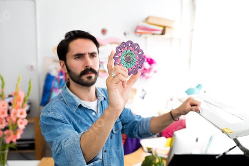 Preview: Young male designer holding up circular print in printing press studio