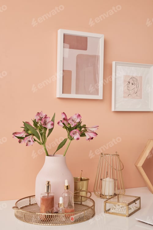 Preview: Two pictures in frames on wall by table with flowers in vase and other stuff
