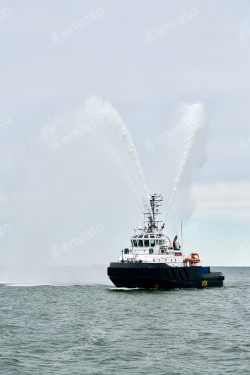 Preview: Fireboat ship sails on open sea directing jets of water to sides demonstrating bravery water salute