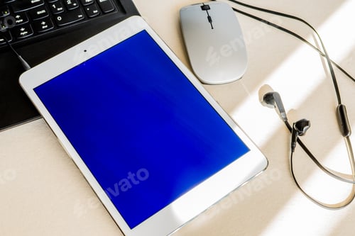 Preview: Tablet with blue screen on the keyboard of a laptop on a desk - technology and business concept