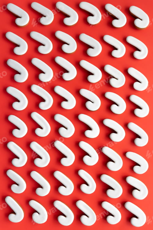 Preview: A lot of gingerbread candy cane shaped cookies on a red background.