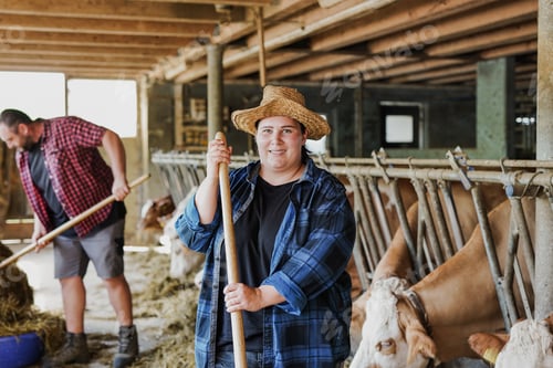 Preview: Happy young farmer couple working inside cowshed