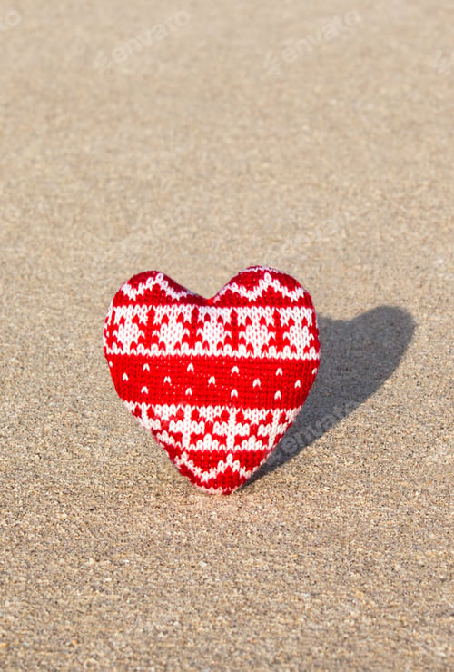 Preview: red knitted heart on sea sand