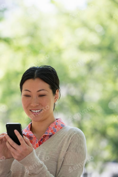 Preview: Summer in a city park. Business people on the move. A woman checking her smart phone for messages.