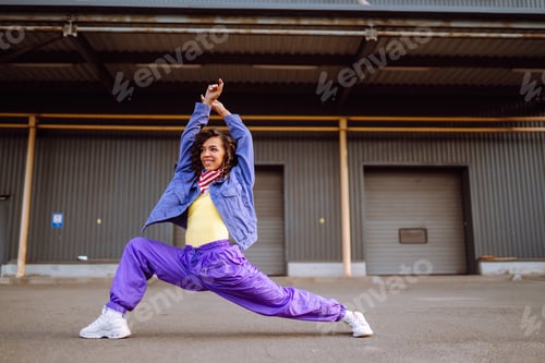 Preview: Funky young woman with american bandana dancing alone in the street.Sport, dancing and urban culture