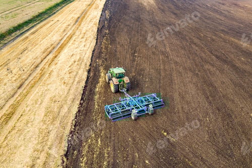 Preview: Aerial view of a tractor plowing black agriculture farm field after harvesting in late autumn.