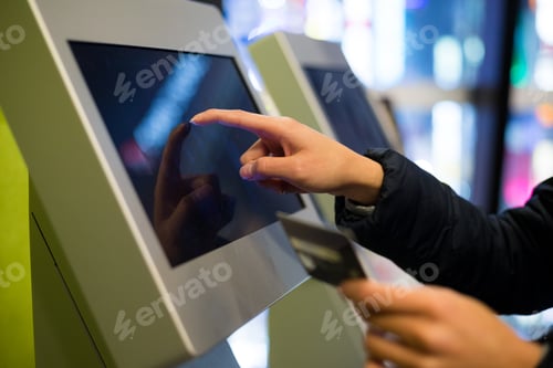 Preview: Woman paying at ticket machine in cinema
