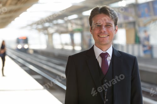 Preview: Portrait of happy businessman smiling at train station