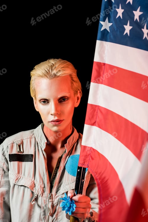 Preview: attractive female astronaut in spacesuit holding american flag, isolated on black
