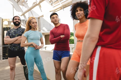 Preview: group of multiracial sportsmen standing resting while training together outdoors