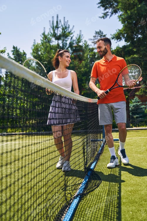 Preview: Two smiling sportspeople with rackets looking at each other