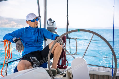 Preview: Young man captain stands at the helm and controls a sailboat during a journey by sea