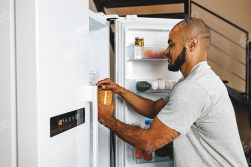 Preview: African american man taking food from a fridge in his house