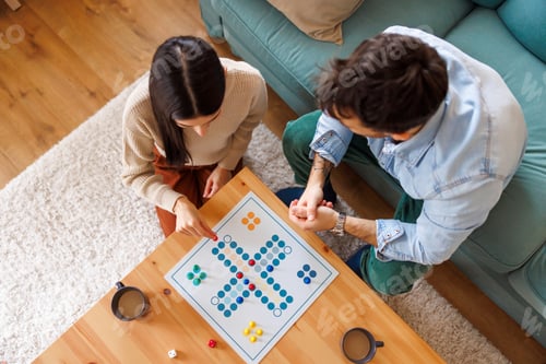 Preview: Couple having fun playing board game while relaxing at home