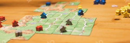 Preview: men friends have fun playing the carcassonne board game at night. game cards and chip