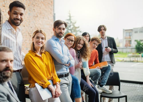 Preview: Portrait of young businessman with group of entrepreneurs indoors in office, looking at camera