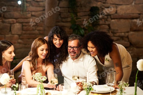 Preview: Pretty mature woman in elegant dress scrolling through photos in smartphone