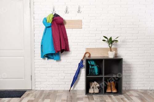 Preview: Stylish hallway interior with shoe rack and hanging clothes on brick wall