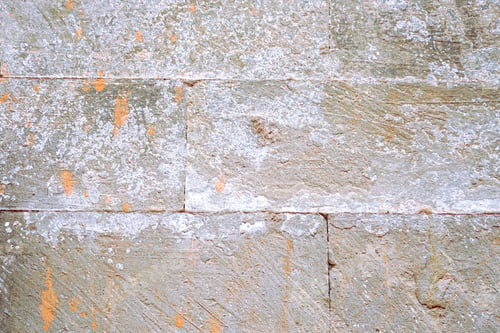 Preview: Close-up of weathered stone wall with mineral deposits showcasing rough texture