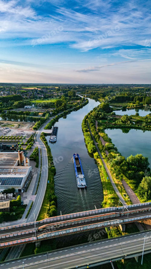 Preview: High-angle shot of a boat going through the Scheldt river during sundown in Oudenaarde, Belgium